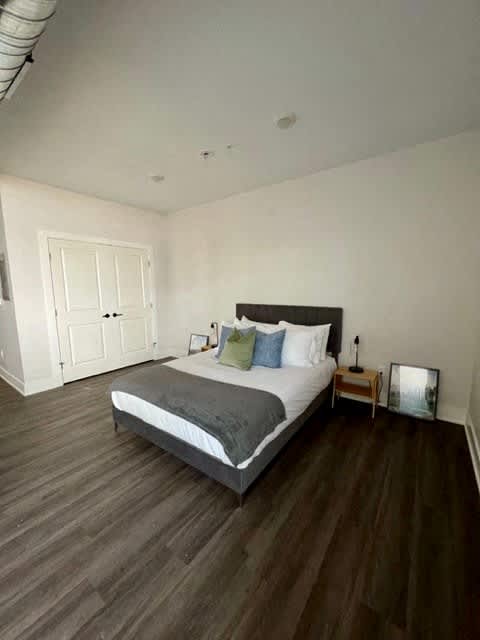 A bedroom with a bed, nightstand, and a wooden floor at Michigan Street Apartment Homes, Grand Rapids  , 49503