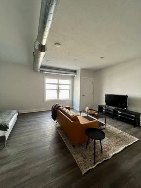 A living room with a grey floor and white walls at Michigan Street Apartment Homes, Grand Rapids  , MI, 49503