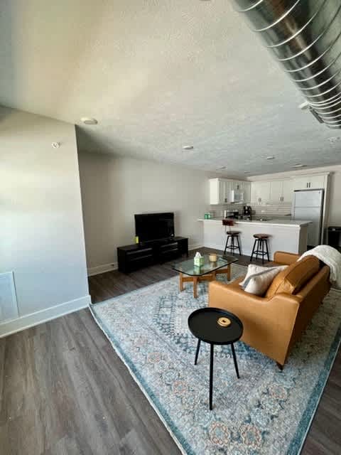 A living room with a brown sofa, a black table, and a patterned rug at Michigan Street Apartment Homes, Apartments, Grand Rapids  , MI