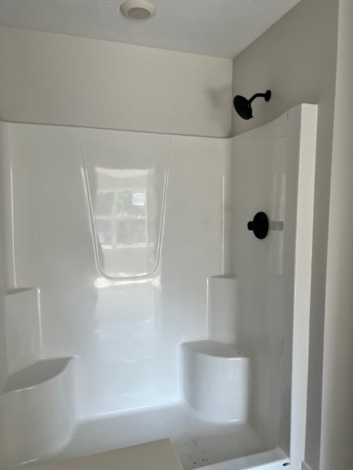 A white bathroom with a glass shower door at Michigan Street Apartment Homes, Grand Rapids  , MI, 49503