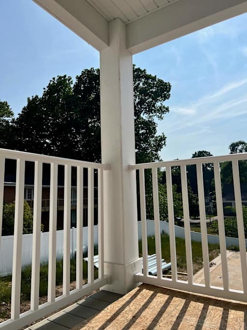 A white porch with a white railing and a white pillar at Michigan Street Apartment Homes, Michigan