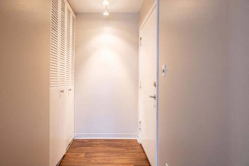 A hallway with a wooden floor and white walls at Michigan Street Apartment Homes, Michigan