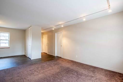 A large, empty room with a carpeted floor and white walls at Michigan Street Apartment Homes, Michigan, 49503