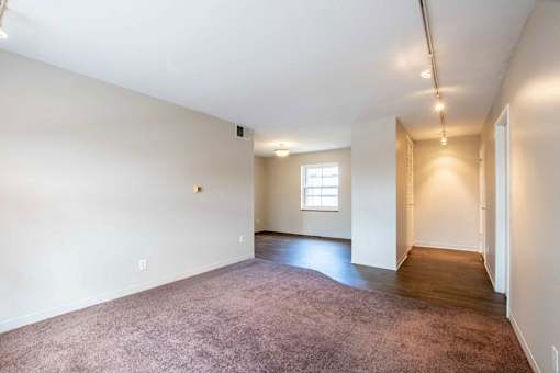 A large, empty room with a carpeted floor and a window at Michigan Street Apartment Homes, Apartments, Grand Rapids  , MI