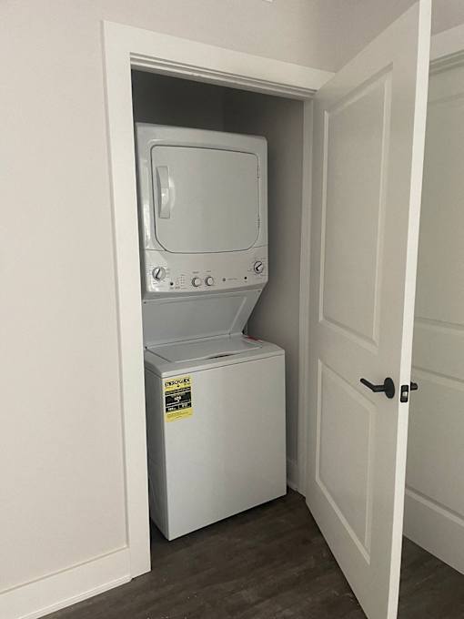 A white dryer is in a small closet at Michigan Street Apartment Homes, Grand Rapids  , 49503