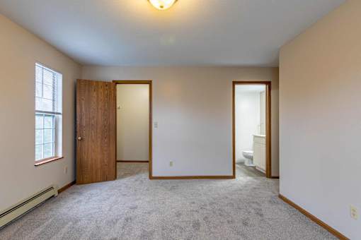 A room with a carpeted floor and a door on the left side.