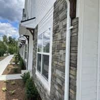 A white house with a grey stone wall and a white window at The Vue at Rivertown Park Townhomes, Wyoming  , Michigan
