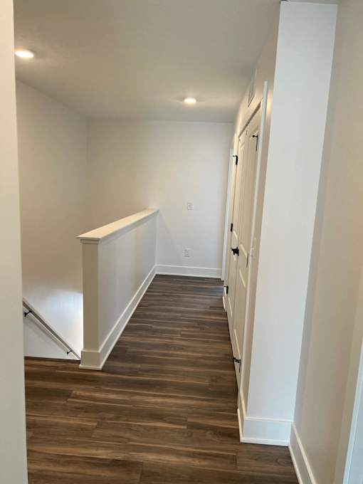 A hallway with wood flooring and white walls at The Vue at Rivertown Park Townhomes, Wyoming  , Michigan