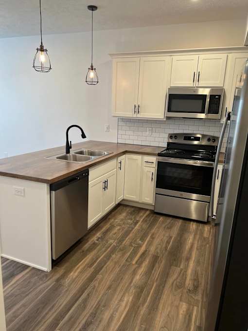 A kitchen with a wooden floor and white cabinets at The Vue at Rivertown Park Townhomes, Michigan