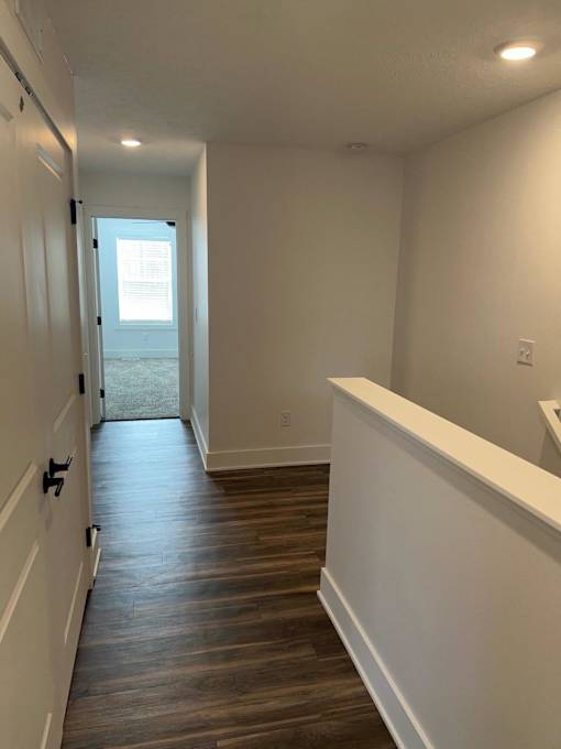 A long hallway with wood floors and white walls at The Vue at Rivertown Park Townhomes, Apartments, Wyoming  , MI
