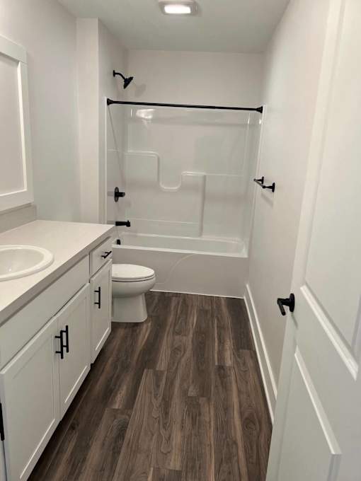A white bathroom with wood flooring and a walk-in shower at The Vue at Rivertown Park Townhomes, Wyoming  