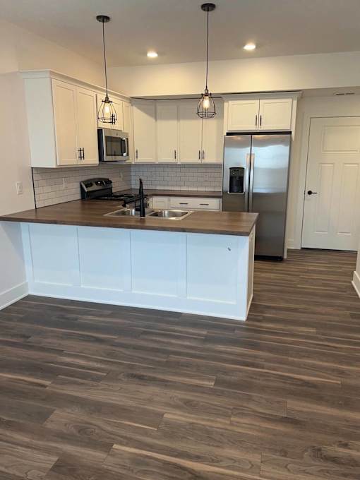 A kitchen with white cabinets and a wooden floor at The Vue at Rivertown Park Townhomes, Wyoming  , MI, 49418