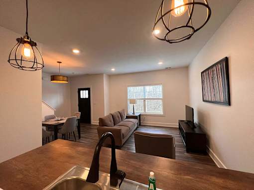 A modern living room with a brown couch and a wooden floor at The Vue at Rivertown Park Townhomes, Wyoming  , MI, 49418