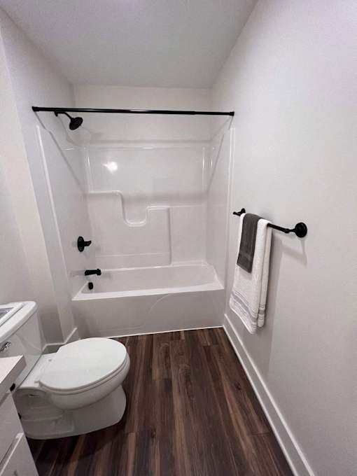 A white toilet sits next to a white bathtub in a small bathroom at The Vue at Rivertown Park Townhomes, Wyoming  