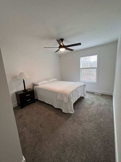 A bedroom with a bed, nightstand, and fan at The Vue at Rivertown Park Townhomes, Wyoming  , MI, 49418
