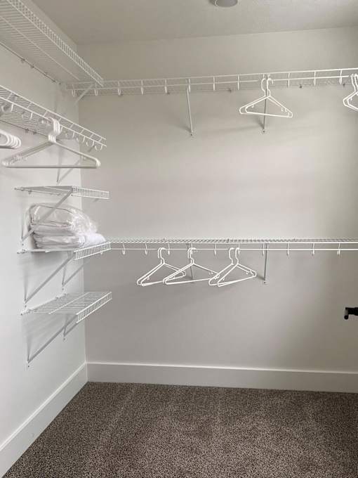 A white closet with hangers and shelves at The Vue at Rivertown Park Townhomes, Michigan, 49418
