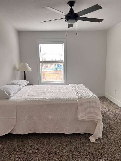 A bedroom with a bed, a ceiling fan, and a window at The Vue at Rivertown Park Townhomes, Apartments, Wyoming  , MI