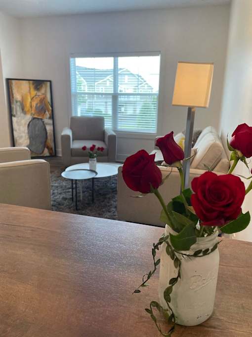A vase with red roses sits on a wooden table at The Vue at Rivertown Park Townhomes, Wyoming  , 49418