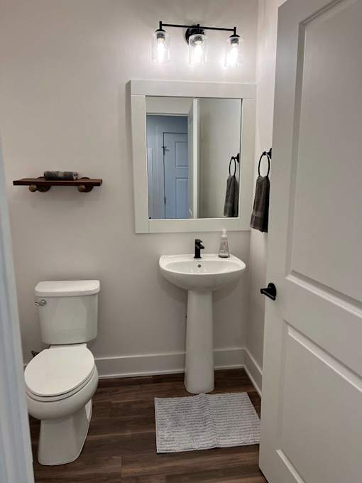 A white toilet sits next to a white pedestal sink in a small bathroom at The Vue at Rivertown Park Townhomes, Apartments, Wyoming  , MI