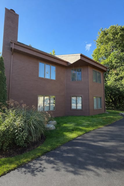 A house with a brown siding and a brown roof with a chimney.