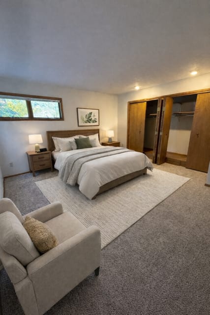 A bedroom with a large bed and a chair.