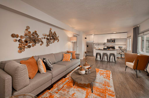 A living room with a grey couch and orange pillows