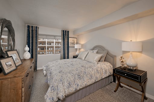 A bedroom with a bed, nightstand, and a dresser with a mirror