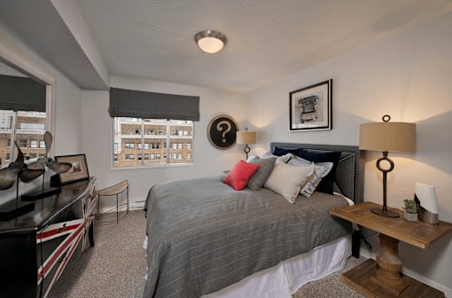 A bedroom with a bed, a desk, and a chair