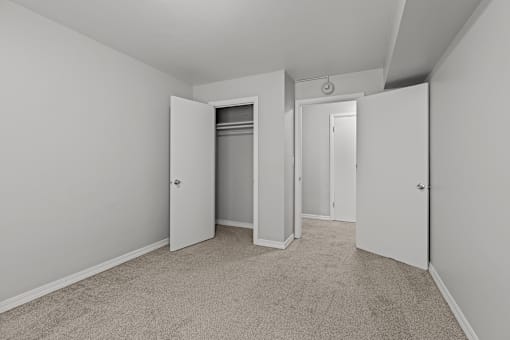 A room with carpeted floors and three doors.