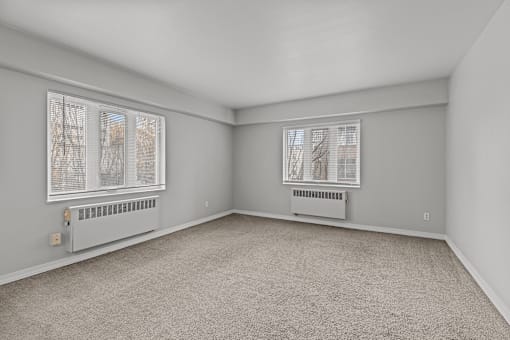 A room with a carpeted floor and two windows.