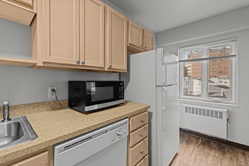 A kitchen with a black microwave, white fridge, and brown cabinets