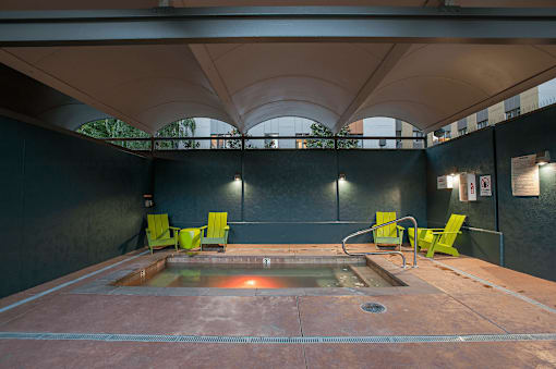 A hot tub is surrounded by four chairs in a room with a black wall