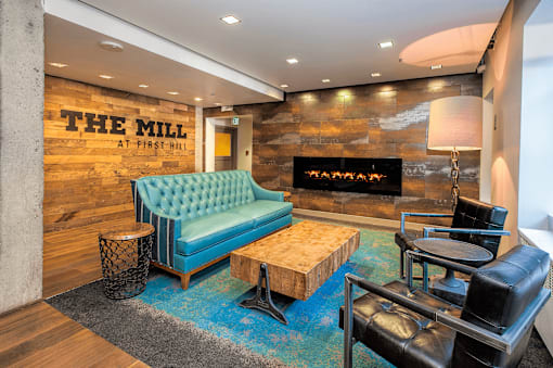 A blue sofa sits in front of a stone wall with a fireplace