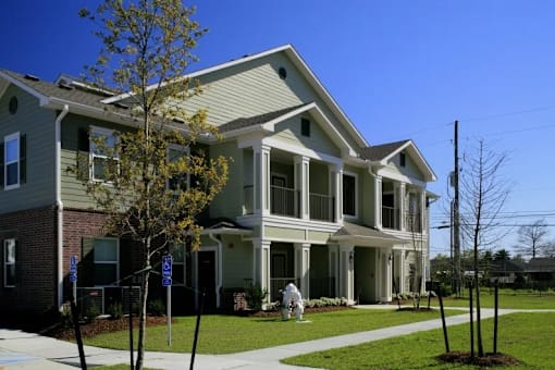 A person in a white coat is standing outside a two-story house.