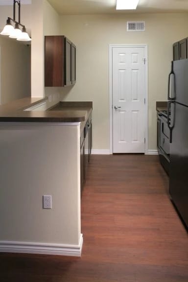 A kitchen with a white door and a black refrigerator.