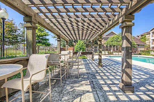A patio with a table and chairs under a wooden pergola.