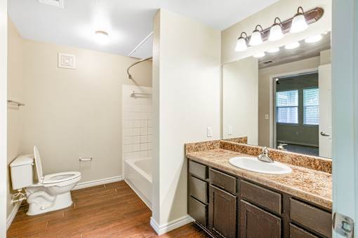 A bathroom with a toilet, sink, and mirror.