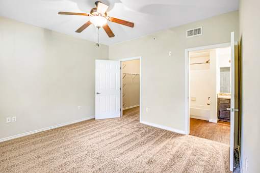 A room with a ceiling fan and carpeted floor.