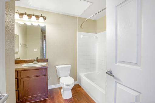 A white toilet sits next to a white bathtub in a bathroom.