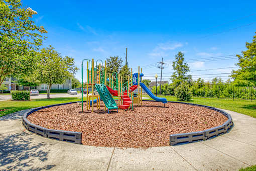 A playground with a red slide and green and yellow play structures.
