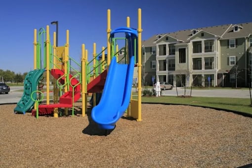 A playground with a blue slide and a red slide.