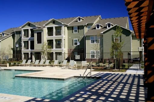 A large apartment complex with a pool in front.