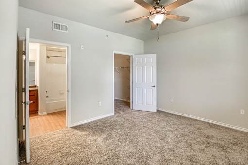 A room with a ceiling fan and carpeted floor.