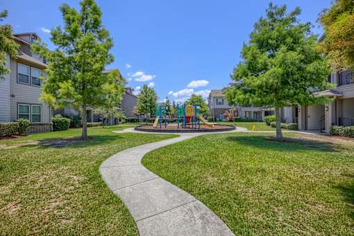 A playground with a slide is surrounded by houses and trees.