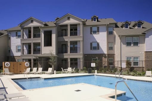 A large apartment complex with a pool in front.