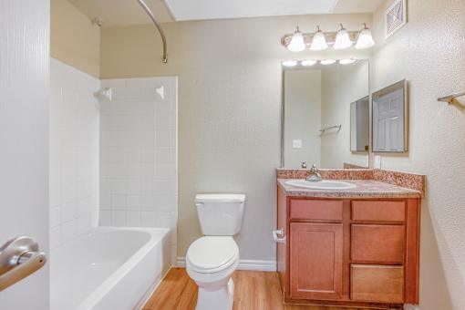 A white toilet sits next to a white bathtub in a bathroom.
