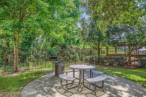 A picnic table surrounded by four benches in a park.