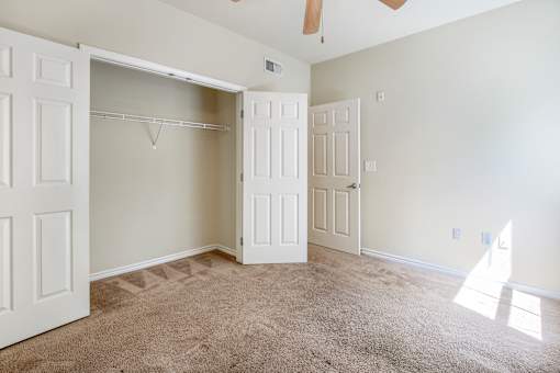 A room with a carpeted floor and a ceiling fan.