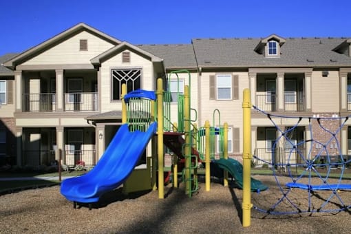 A playground with a blue slide and a yellow and green climbing frame.