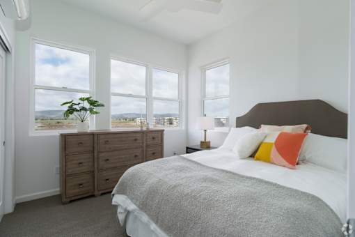 A bedroom with a large bed and a view of the mountains through the windows.